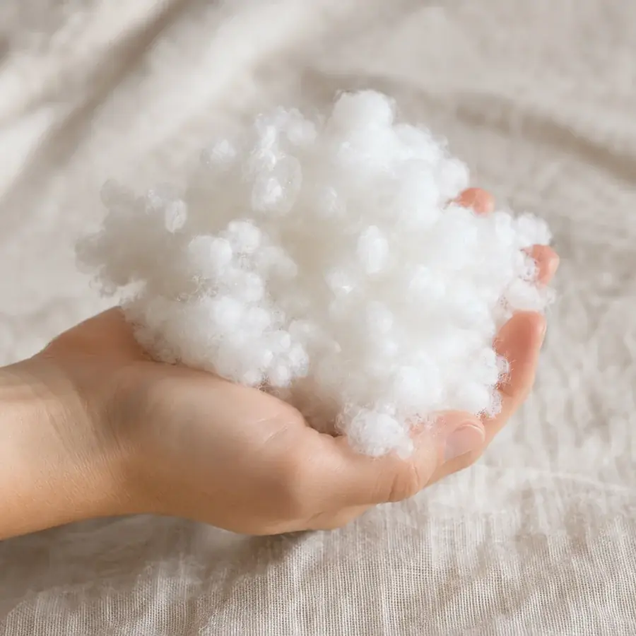 A handful of lofty white synthetic fiber held in an open hand
