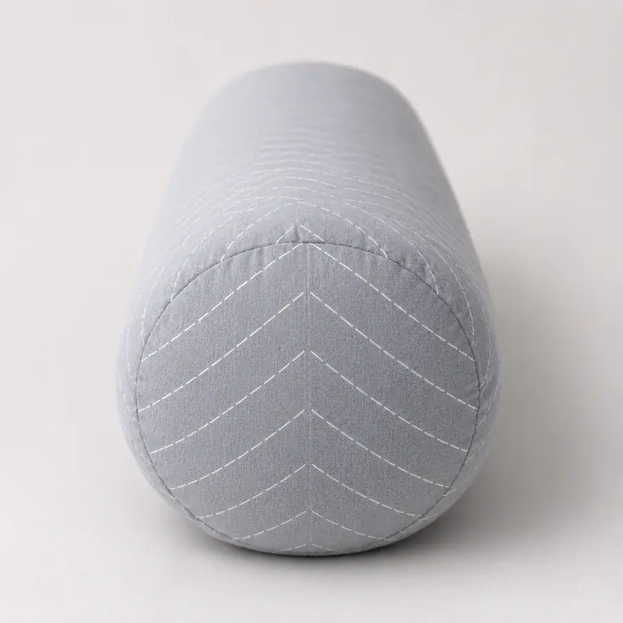 Pregnancy pillow seen end-on, the thickness of the bolster readable against a neutral background