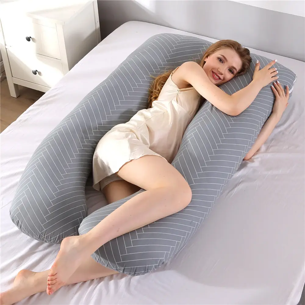 Grey herringbone U-shaped pregnancy pillow on a made bed in a bright bedroom