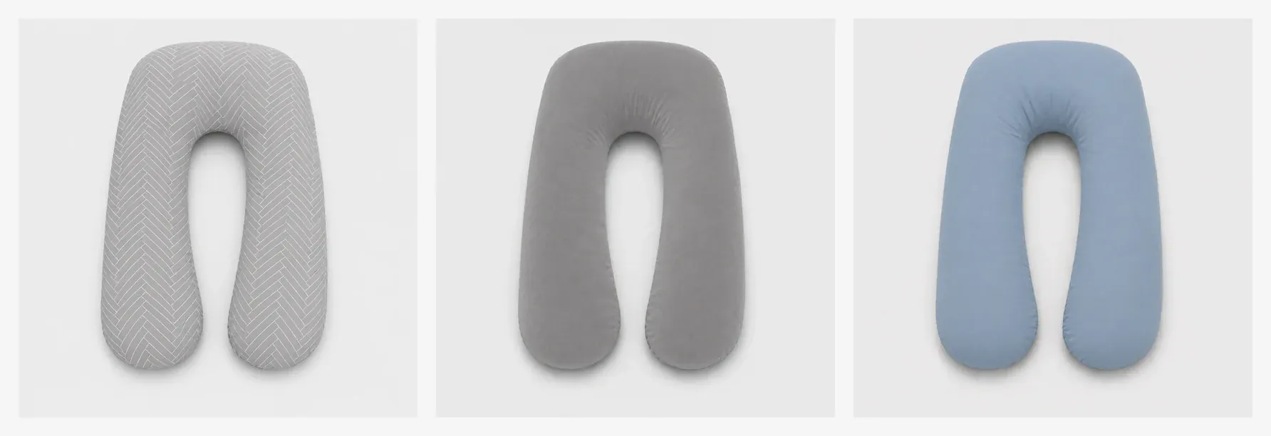 The pregnancy pillow’s three colors side by side on a light background: herringbone gray, plain gray and blue